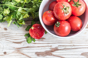 Fresh tomatos and herbs on wooden background. Summer salad.