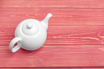 White ceramic tea kettle on wooden table close up