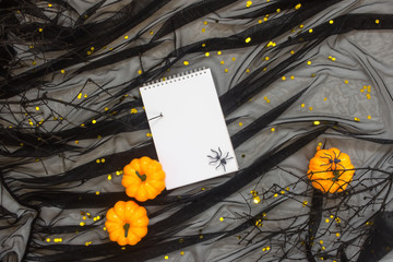 Decorative Pumpkins on Shiny background with black tulle strewn with golden confetti. Halloween decorations  with spiders and snags. Flat lay, top view trendy holiday concept.