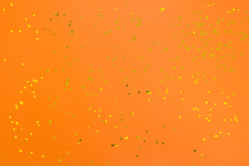 Orange halloween background with golden confetti. Festive surface.  Flat lay, top view.