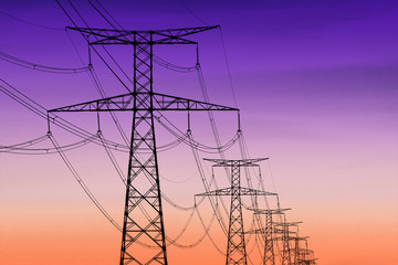 high voltage pylons silhouette , sunset lighting, clear sky background