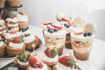 candy buffet with white souffle in glasses. Toned image.Buffet with sweets. Cakes with strawberries and blueberry. Sweet table for banquets, weddings, parties. Candy bar.The holiday table decoration.