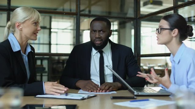 Male employee showing stop gesture to arguing female colleagues, disagreement