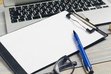 Clipboard with blank paper for copy space and supplies on wooden table