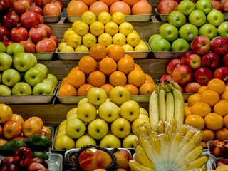 Fresh oranges, apples, bananas, lemons, pomegranades on a showcase at marketplace