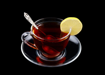 Transparent cup of tea with spoon and lemon isolated on black