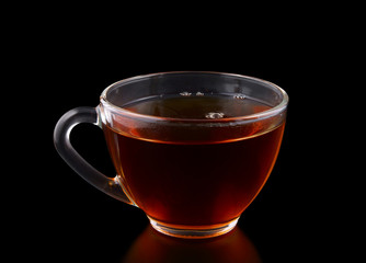 Glass cup of tea on black background