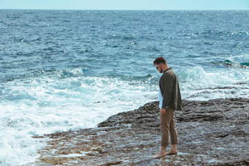 man walking by rocky beach in windy day summer vacation. enjoy sea view