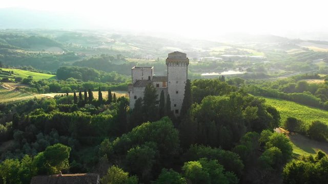 Aerial view of an old stone villa surrounded by trees and shrubs hills in a beautiful location on a sunny warm summer day. Concept of medieval tourist objects in Europe