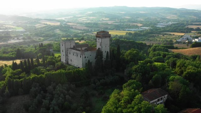 Aerial view of a beautiful monumental stone medieval villa located on a hill among the trees and shrubs in a picturesque location in Europe. Heritage concept of the Middle Ages and t
