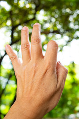 Trigger Finger lock on thumb and index finger of woman's back left hand, Suffering from pain, in bokeh green garden background, Close up & Macro shot, Office syndrome, Health care concept