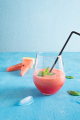 Watermelon melon strawberry smoothie. Summer cocktail with ice and mint on a blue turquoise background with copy space. Vertical