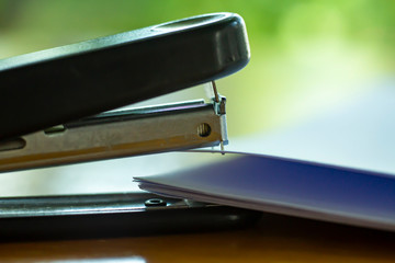 Stapler and stapling white paper on bokeh green garden background, Problem Process, Close up &...