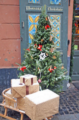 Fototapeta na wymiar Christmas tree decorated with festive balls and garlands stands on a street covered with snow.