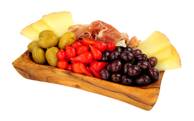 Assortment of Spanish tapas with Serrano ham, Queen green olives, sweet flame peppers and Manchego cheese in an olive wood bowl isolated on a white background