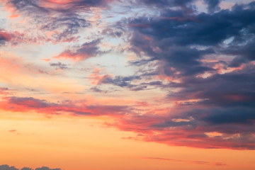 Heavenly summer background. Beautiful bright majestic dramatic evening sky at sunset or sunrise orange and blue with rays. The sun shines over the horizon against the backdrop of thunder clouds