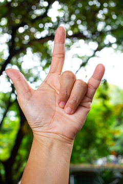 Woman's fore hand  symbol meaning " i love you " in bokeh green garden background,  Asian body skin part, Symbol, Gesturing, Body Language Concept