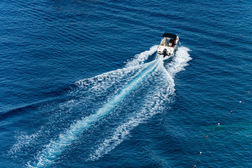 White motorboat in motion with wake in the blue Mediterranean sea photographed from above. Cinque...