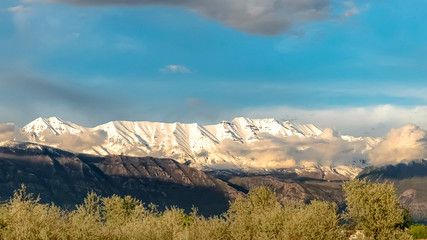 Panorama frame Scenic nature view with majestic snow peaked mountain under cloudy blue sky