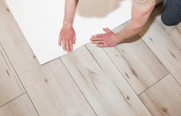 Man is holding roll wallpaper in hands on floor. Maintenance repair works renovation in the flat. Restoration indoors.