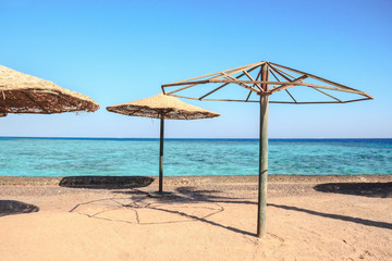Obraz na płótnie Canvas Abandoned beach umbrellas on desert beach, Egypt resort at tourism crisis period
