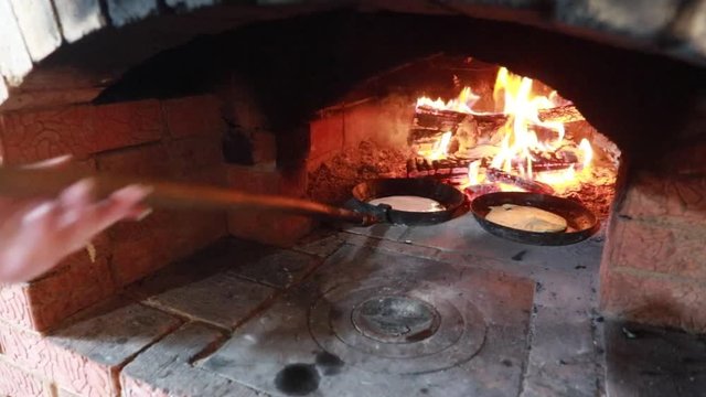 Cooking in the fireplace. Pancakes in a pan are fried on a fire in the oven