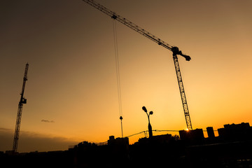 Industrial landscape with silhouette of crane on the sunset background