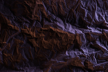 top view of crumpled paper with purple colorful lighting in darkness