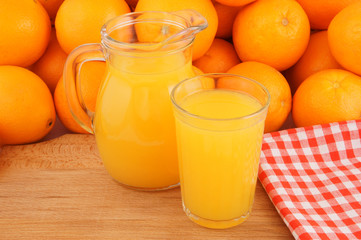 Fototapeta na wymiar Orange juice in pitcher and glass on wooden board