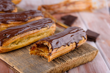 Tasty and beautiful eclairs with chocolate on a wooden board. Appetizing dessert. Party supplies