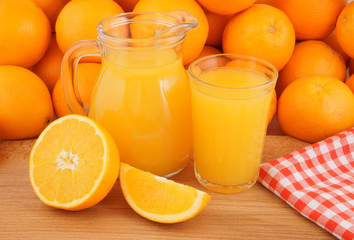 Fototapeta na wymiar Fresh orange juice on wooden table with many oranges as background