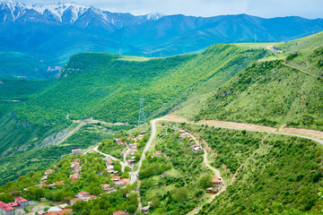 view of the village located in a mountain gorge on a bright sunny day with clouds in the sky.