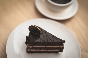 a piece of delicious chocolate cake on a white plate and a cup of hot chocolate