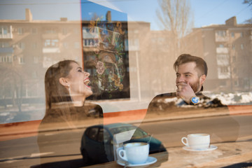 Good looking couple laughing and having a good time on a date in a coffee shop