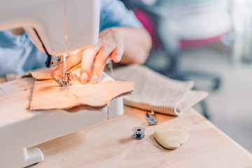 hands of sewing process. Female hands stitching fabric on  machine hobby at home. blurred background.