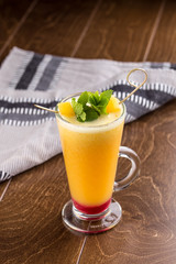 Winter hot drink from oranges and berries in tall glass on wooden table