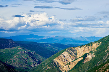 View of mountain snowy ridges on a bright sunny day with clouds in the sky.