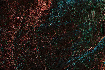 Fototapeta na wymiar abstract background of shiny textured crumpled foil with colorful illumination