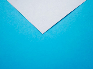 Two colored papers with blue and white flowers. White paper in the form of a triangle on blue. background