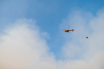 Fire rescue helicopter in the sky, with water bucket, Spain