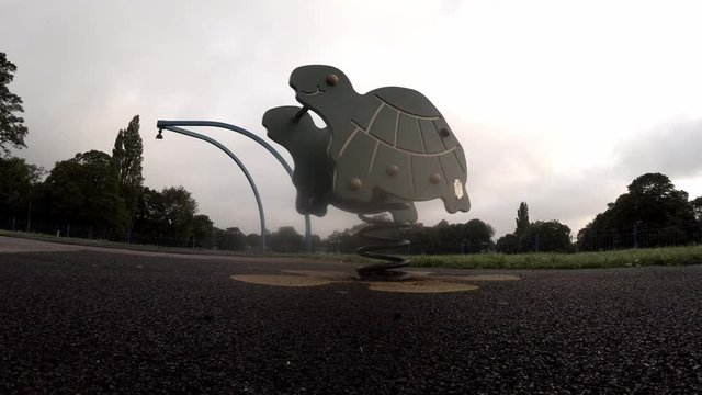 Turtle ride bouncing alone in overcast, cloudy children's playground at daybreak.