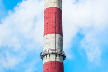 Smoky factory chimney on a background of blue sky.