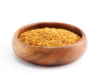 Fenugreek (Trigonella) in a wooden cup on a white background