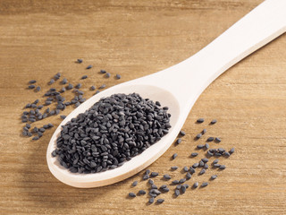 Black sesame (Sesamum indicum) in a spoon on a wooden background diagonally