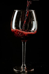 Red wine being poured in a wine glass on a dark background