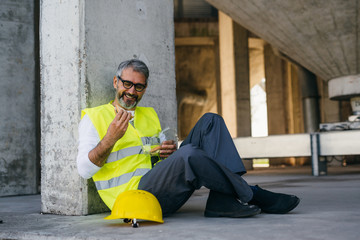 worker on lunch break eating sandwich at construction site