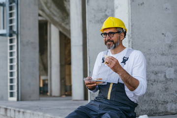 worker on lunch break eating sandwich at construction site