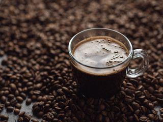 Glass Cup of espresso coffee stands on coffee beans close-up