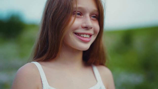 Portrait of sweet little girl in dress outdoor in summer day happily smiling. Good mood, positive emotions, childhood. Child&rsquo;s portrait, close up view. Summertime, sunny weather