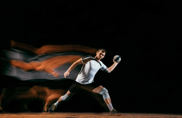 Caucasian young handball player in action and motion in mixed lights over black studio background....